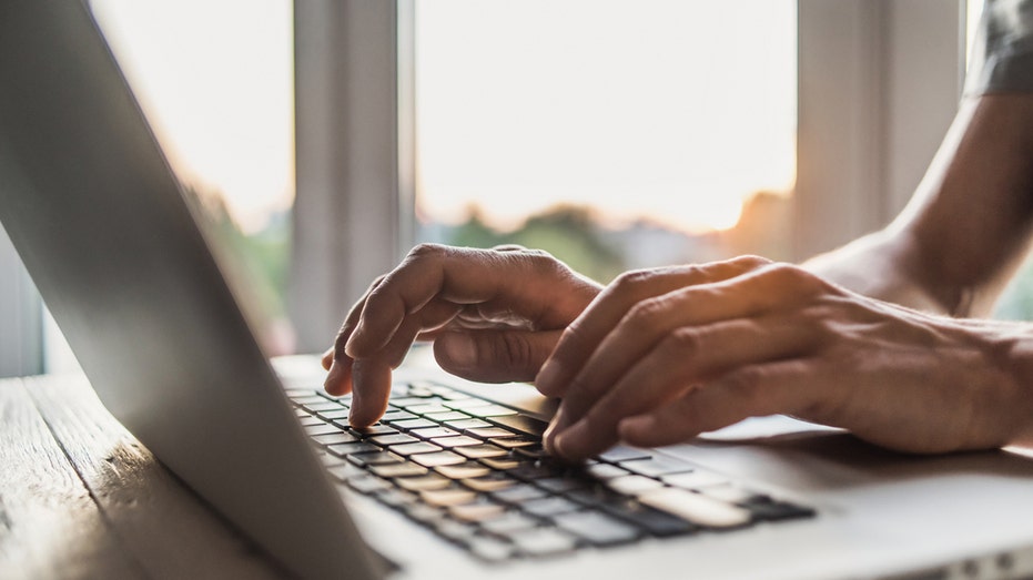 Hands type on laptop