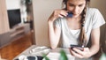 Young woman with braided hair sitting by the table, looking on her smart phone. Paying bills on the phone, checking her finance on the phone app. Millenial generation uses new and improved ways of dealnig with money. Everything can be done over the phone, the need of going to a bank is no longer here. Young generations are paying bills, transferring money, checking their balance  and other things, all over the phone financial and bank apps. - Fox News