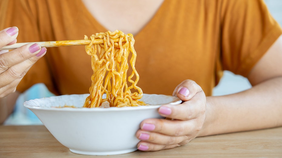 a woman picks up instant noodles with chopsticks