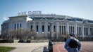 A pedestrian walks a running track while wearing a surgical mask near Yankee Stadium as it remains closed due to COVID-19 concerns, Thursday, March 26, 2020, in the Bronx borough of New York. (AP Photo/John Minchillo)