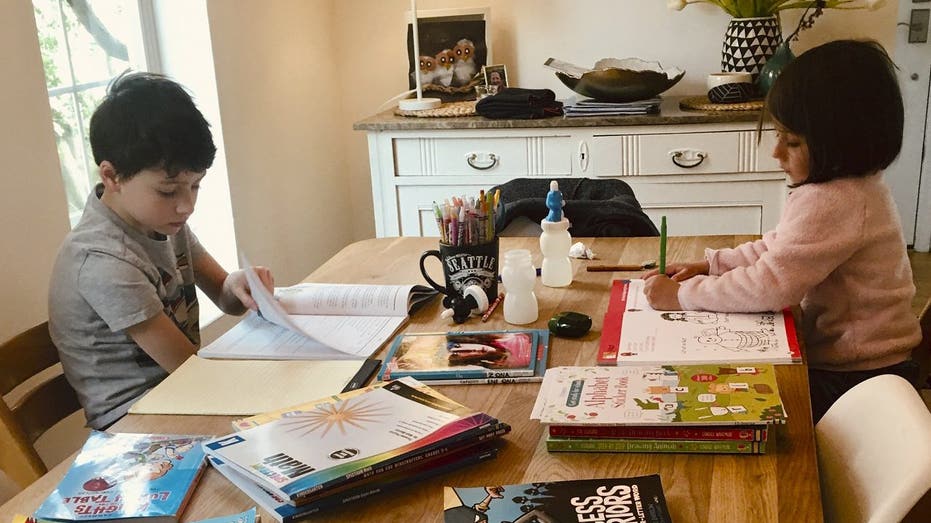 This photo provided by Natasja Billiau shows her two children, Victor, 8, and Anna Laura, 5, studying at the kitchen table in their Seattle-area home Thursday, March 12, 2020, after their school was shut down for weeks due to the coronavirus. 