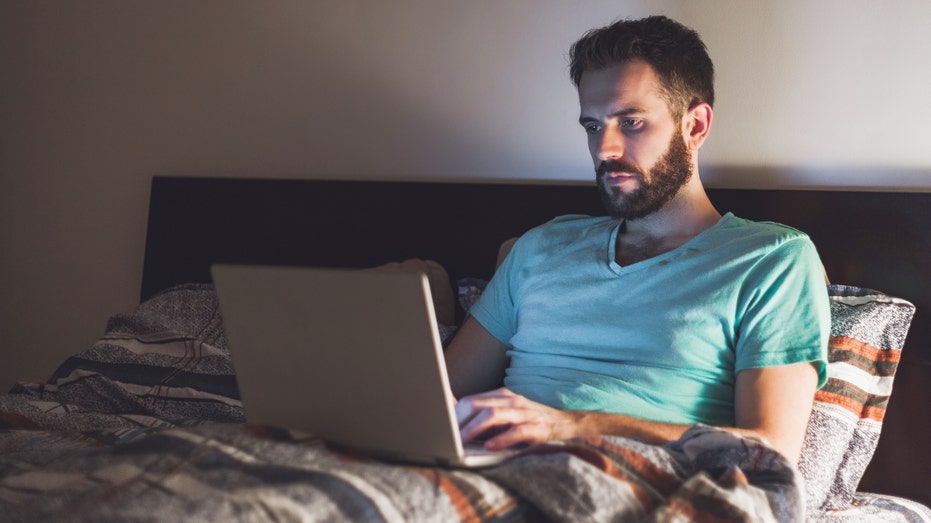 man on laptop in bed