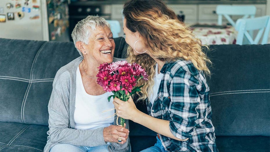 Woman hands flowers to older woman