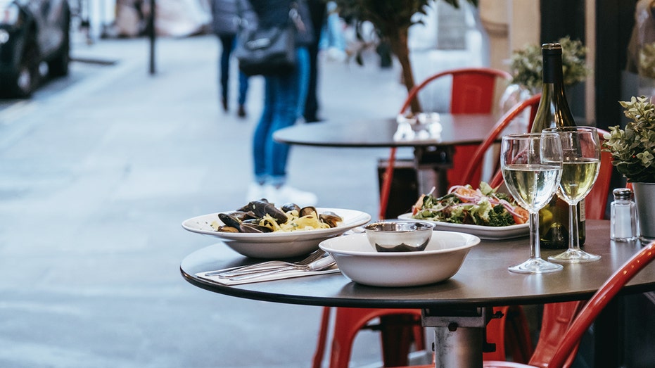 Plates with food and glasses of wine at the outdoor table of a restaurant, selective focus.
