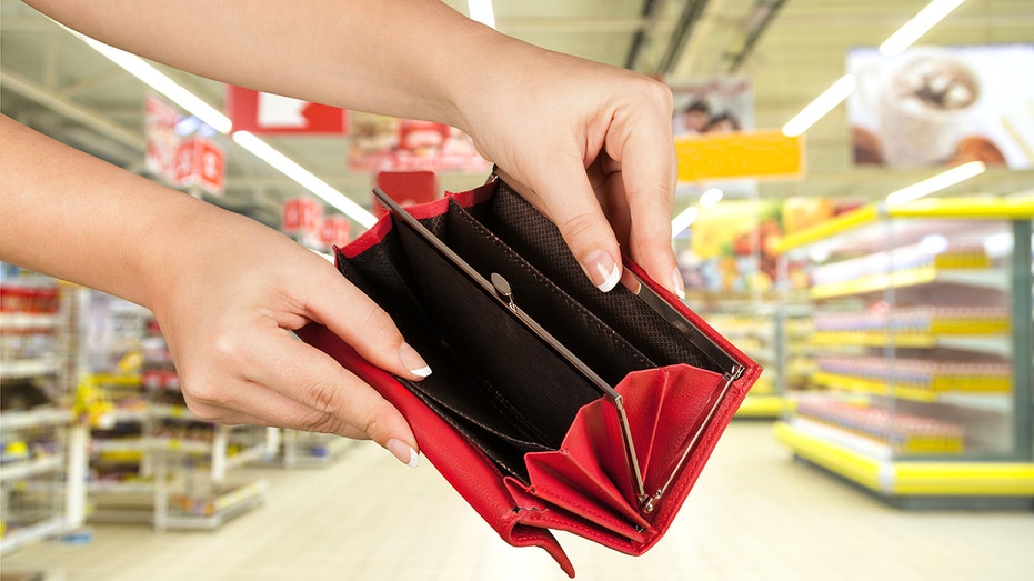 Female hands hold open an empty wallet on a retail store background 