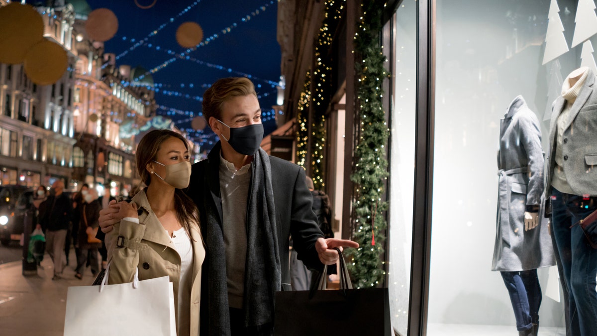 Happy couple wearing facemasks while shopping for their Christmas presents during the COVID-19 pandemic in London