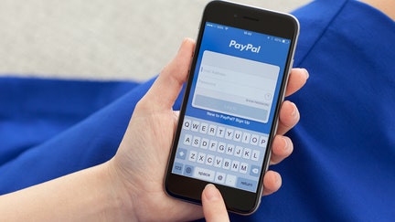 Alushta, Russia - December 3, 2014: Woman holding a iPhone 6 Space Gray with service PayPal on the screen. iPhone 6 was created and developed by the Apple inc. - Fox Business News