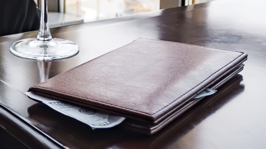 Empty wine glass with tips on the table. View Of Bill And Banknote On Wooden Desk. Paying the bill for the expensive wine. A generous tip. stock photo