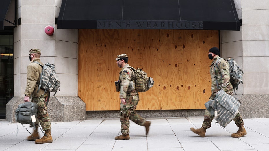 Soldier in front of a boarded building walking to the left