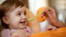 Mother feeding happy toddler girl with a spoon - Fox Business News