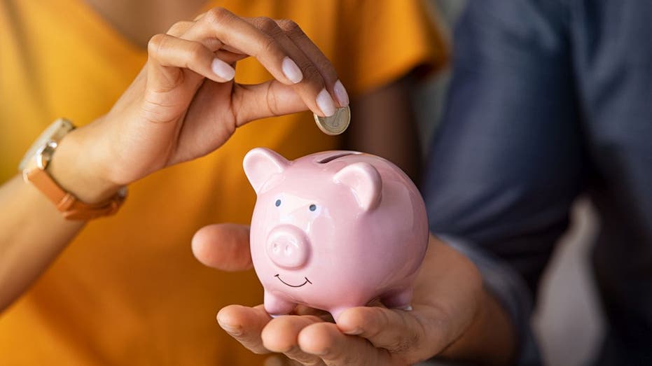 A coin being put into a piggy bank