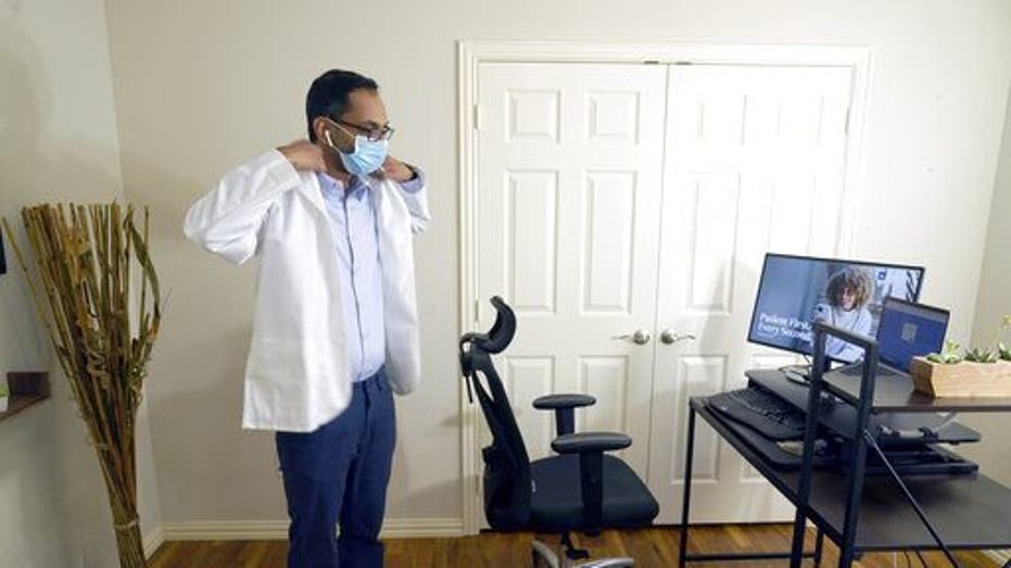 Medical director of Doctor on Demand Dr. Vibin Roy prepares to conduct an online visit with a patient from his work station at home, Friday, April 23, 2021, in Keller, Texas. Some U.S. employers and insurers want you to make telemedicine your first choice for most doctor visits. Retail giant Amazon and several insurers have started or expanded virtual-first care plans to get people thinking telemedicine routinely, even for annual checkups. (AP Photo/LM Otero)