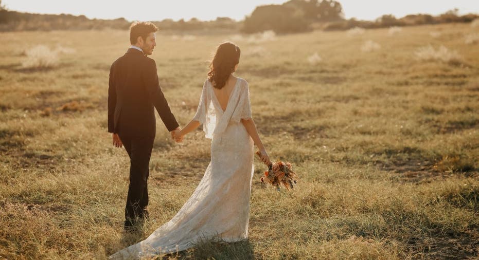 Married couple walks in grassy field