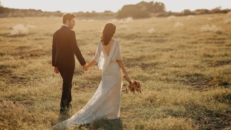 Married couple walks in grassy field