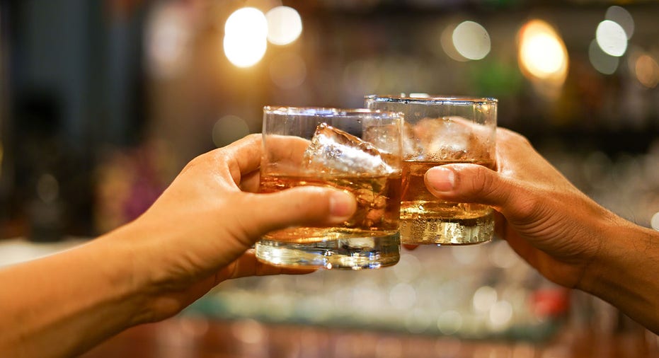 two men clinking glasses of whiskey drink alcohol beverage together at counter in the pub