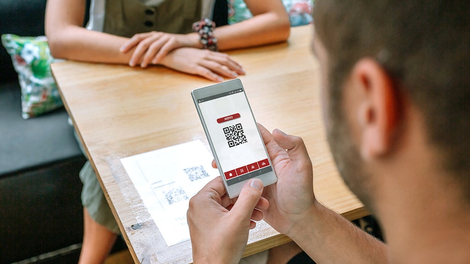 Man a restaurant looks at qr code on phone