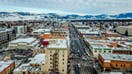 Aerial View of Main Street in downtown Bozeman Montana. Winter snow is scattered on streets and buildings with the mountain range covered in snow in the distance. Famous Baxter Hotel Sign is seen up close.