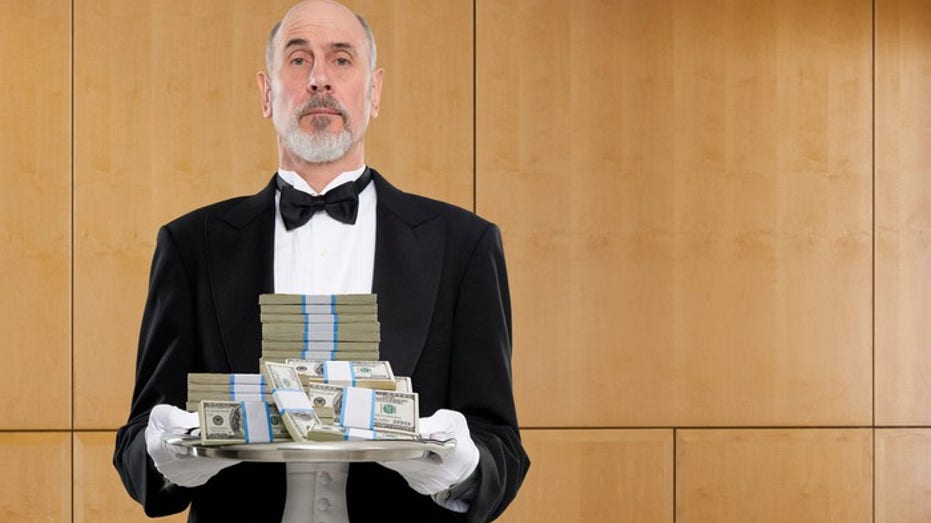 Butler holding platter of cash