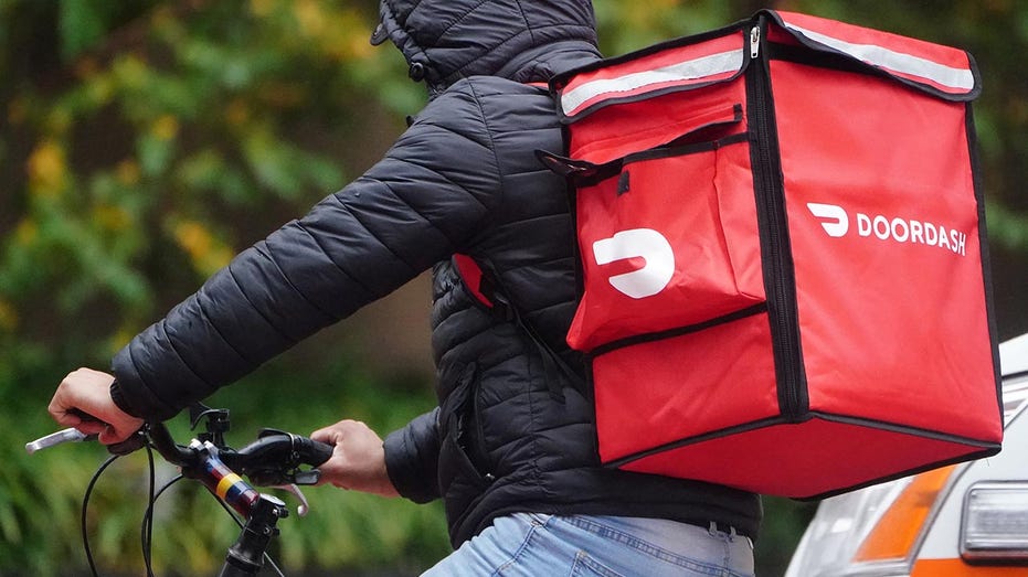 DoorDash delivery person in black coat seen delivering order on bike