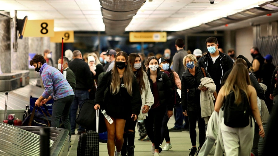 Travelers wearing protective face masks to prevent the spread of the coronavirus disease (COVID-19) reclaim their luggage at the airport in Denver, Colorado, Nov. 24, 2020. 