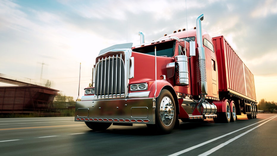 A stock photo of a red big rig truck on a highway.