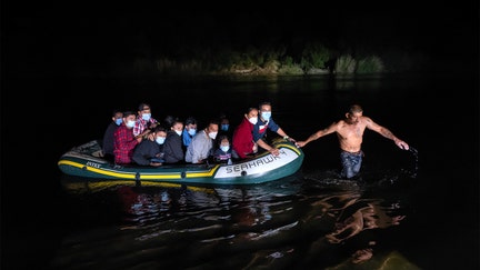 A smuggler guides a group of immigrants across the Rio Grande to cross the border from Mexico on August 14, 2021 in Roma, Texas. (Photo by John Moore/Getty Images)
