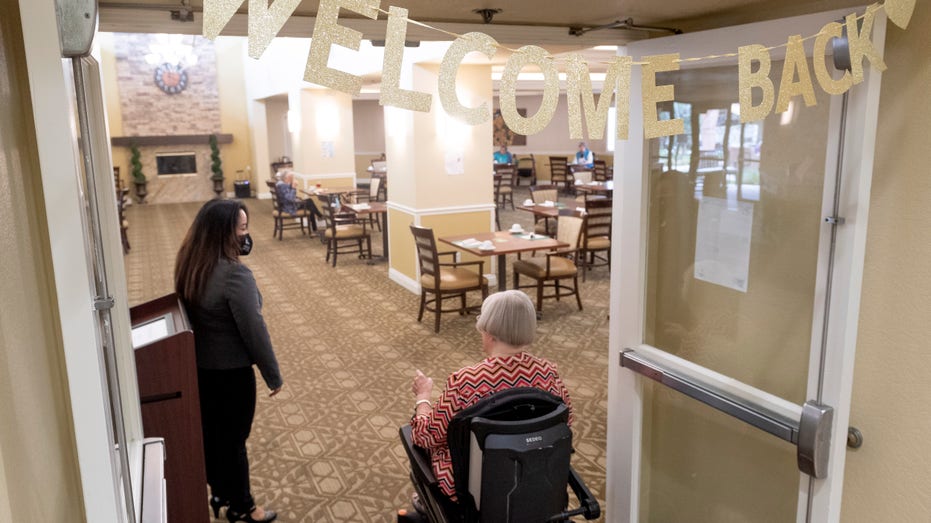 Executive Director Patricia Gustin greets residents at the dining room at Emerald Court in Anaheim, California, on Monday, March 8, 2021.