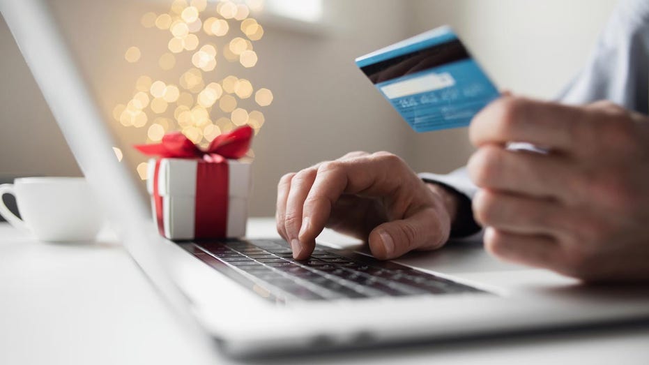 Person entering credit card details on laptop next to Christmas tree
