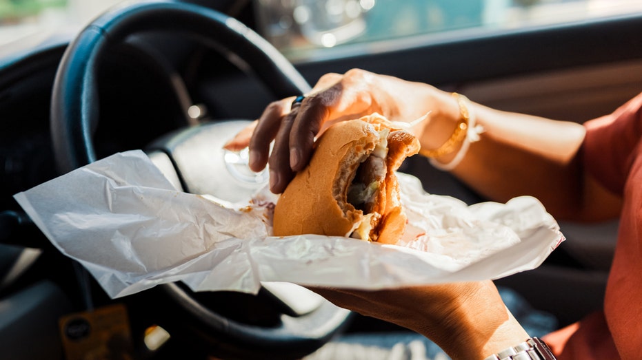 Man eats burger in car