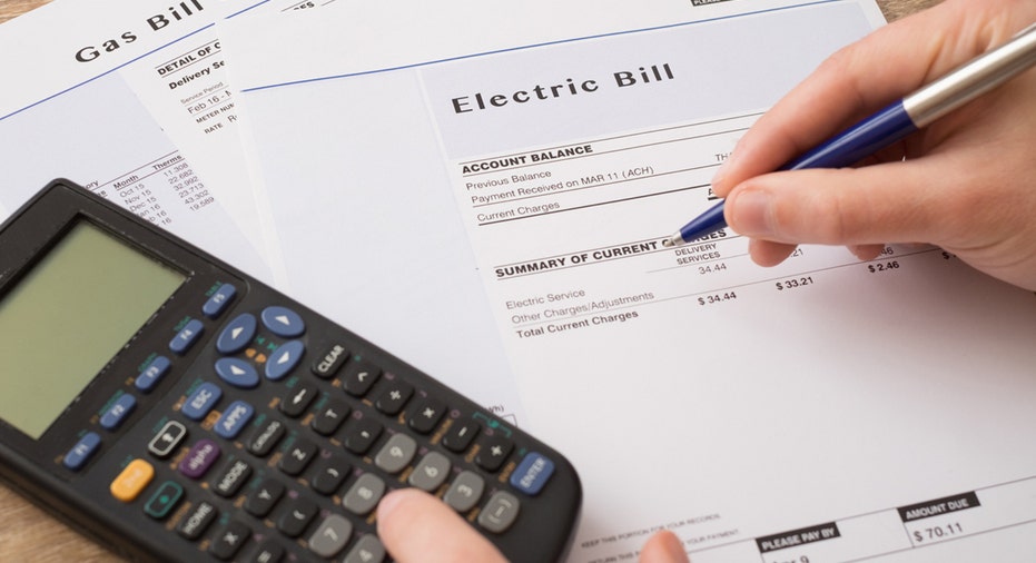 Person signs electric bill with calculator nearby