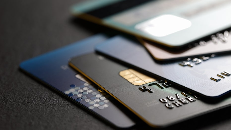 A stack of multicolored credit cards on black background. 