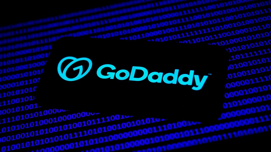 GoDaddy logo displayed on a phone screen and a laptop keyboard in this illustration photo taken in Krakow, Poland, on Nov. 22, 2021.