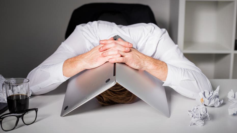 man hiding under laptop