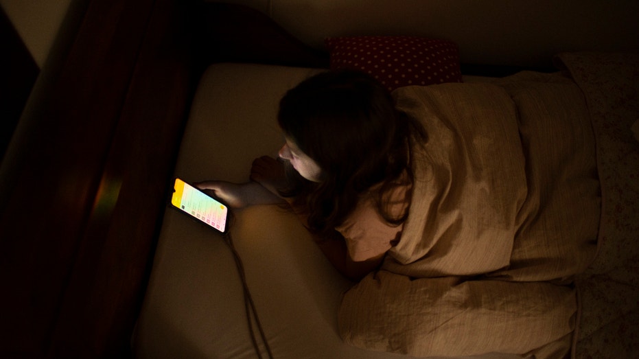 April 16: In this photo illustration a girl looks at the screen of her smartphone on April 16, 2021 in Bonn, Germany. (Photo by Ute Grabowsky/Photothek via Getty Images)