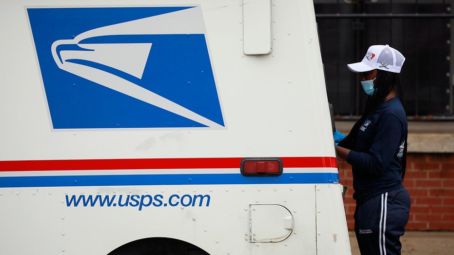 postal worker loading mail truck