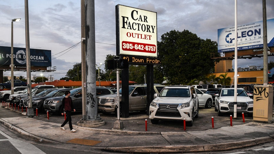 A pedestrian walks past a pre-owned car sales lot in Miami, Florida, on January 12, 2022. 