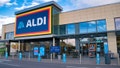 The frontage and brand logo of a branch of German discount retailer Aldi, taken in a local retail park on Wirral, UK on a sunny afternoon