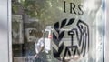 The reflection of a pedestrian is seen walking past an Internal Revenue Service (IRS) office building in the East Harlem neighborhood of New York. Five current and former IRS employees in Tennessee and Mississippi have charged with a fraud scheme to obtain COVID-19 relief funds, authorities said. - Fox News