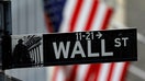A Wall Street sign in front of an American flag