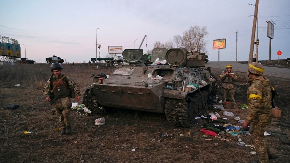 Ukrainian soldiers are seen next to a wrecked armored vehicle they said belonged to the Russian army, outside Kharkiv