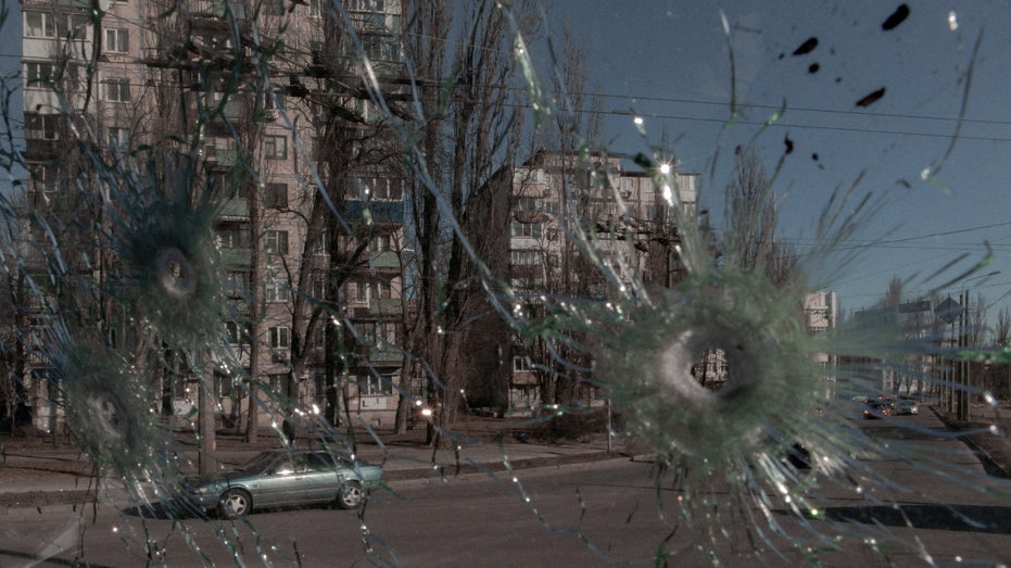 Cars are seen through the damaged window of a vehicle hit by bullets in Kyiv