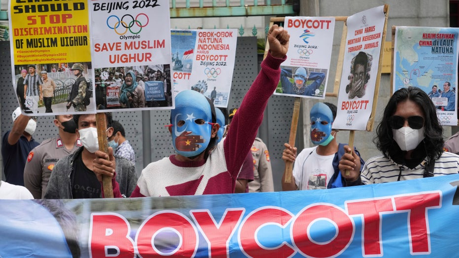 Student activists, some wearing masks with the colors of the pro-independence East Turkistan flag, shout slogans during a rally to protest the Beijing 2022 Winter Olympic Games.