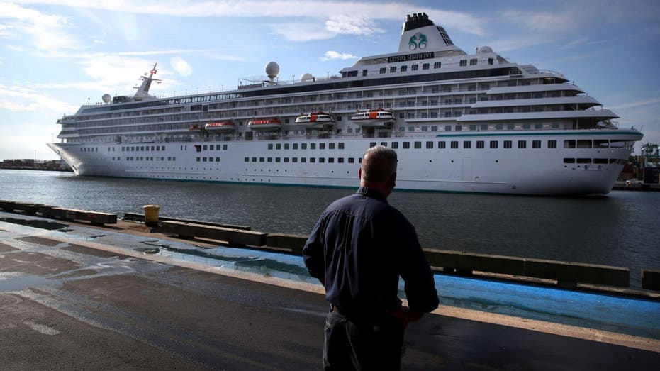 A pedestrian watches as the Crystal Symphony cruise ship arrives at Flynn Cruiseport in Boston, MA on August 18, 2021. The ship is scheduled to depart Sunday for a weeklong trip to Bermuda.