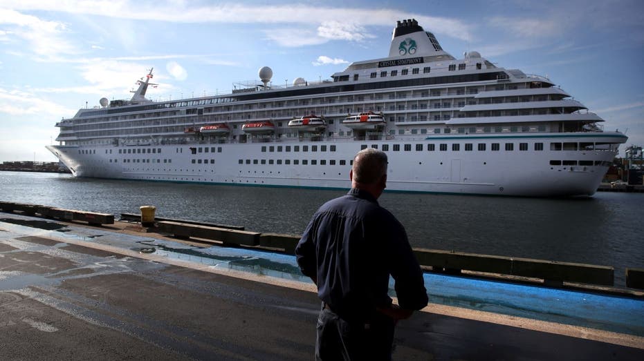 A pedestrian watches as the Crystal Symphony cruise ship arrives at Flynn Cruiseport in Boston, MA on August 18, 2021. The ship is scheduled to depart Sunday for a weeklong trip to Bermuda.