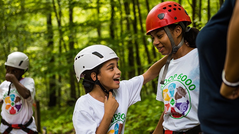 Girl Scouts wearing harnesses and helmets.
