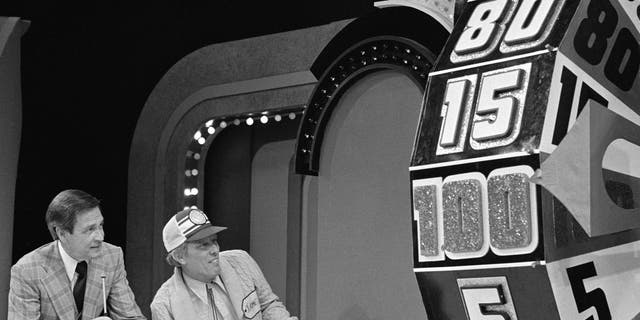 Bob Barker and a contestant look on as the Big Wheel spins on the game show "The Price Is Right" in February 1978.