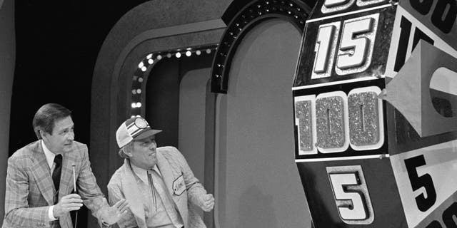 Bob Barker and a contestant look on as the Big Wheel spins on the game show "The Price Is Right" in February 1978.