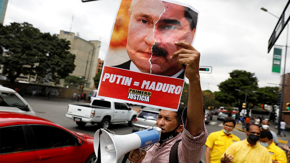 demonstrator holds a collage of pictures of Russia's President Vladimir Putin and his Venezuelan counterpart Nicolas Maduro