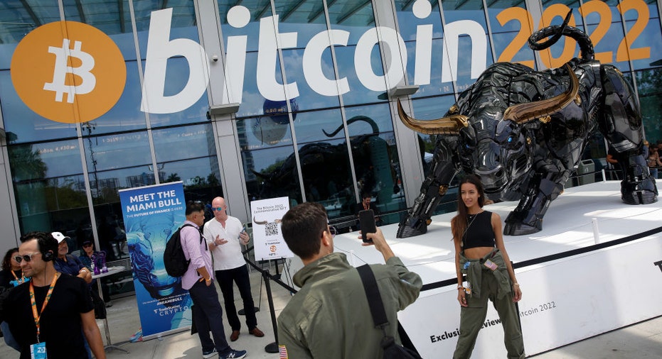 Attendees pose for photos in front of The Miami Bull during the Bitcoin Conference