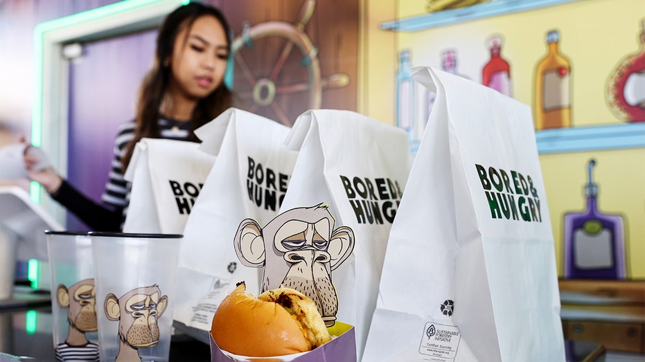 A worker prepares to pick up a to-go bag for a customer at the grand opening of the Bored &amp; Hungry pop-up burger restaurant, which uses NFT art for its branding, on April 9, 2022 in Long Beach, California. (Photo by Mario Tama/Getty Images)